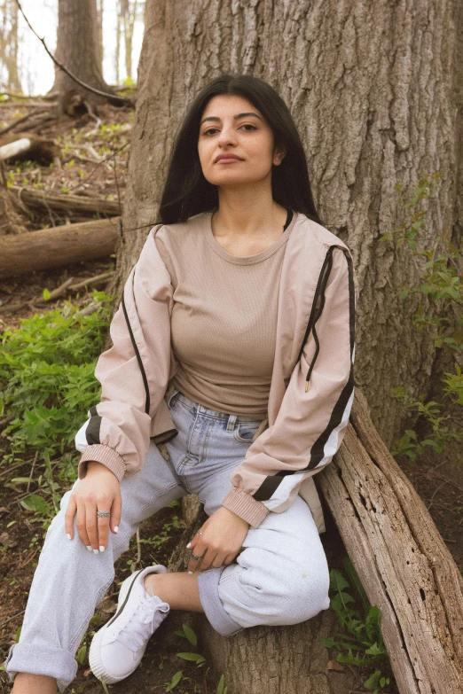 a woman is sitting on a bench by a tree