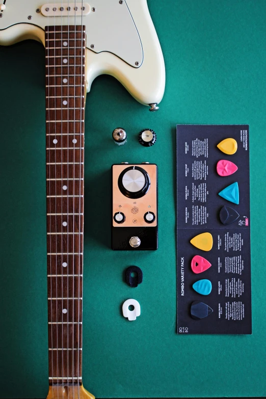 a guitar sitting on top of a green table, adafruit, package cover, cream, multi chromatic