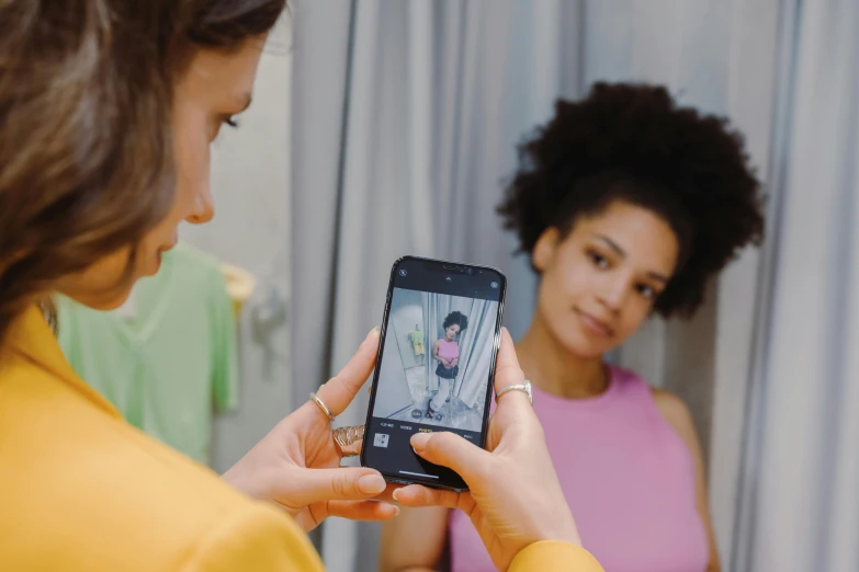 a woman is taking pictures with her phone while standing next to a mirror
