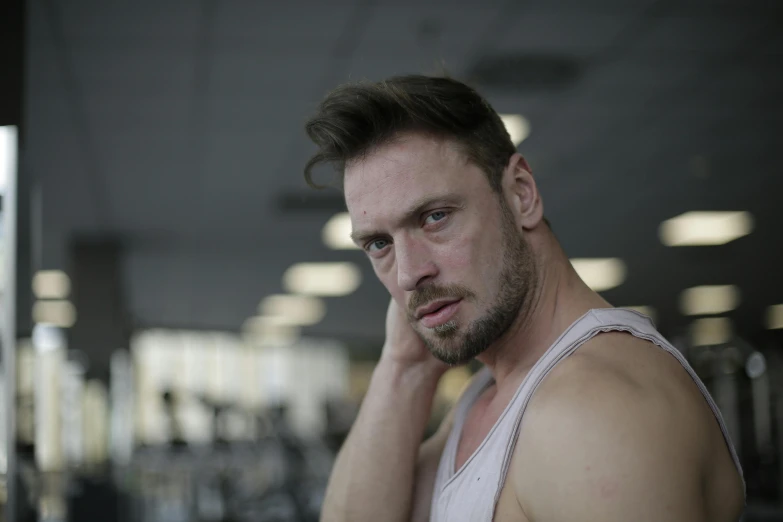 man in vest looking into camera with weight rack on either side