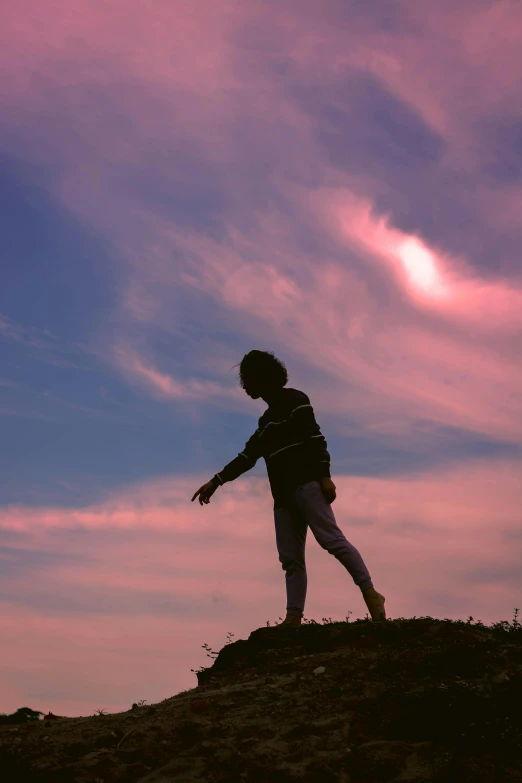 a person standing on a hill with a kite in the sky, an album cover, pexels contest winner, happening, pink clouds, walking boy, silhouette :7, standing on boulder