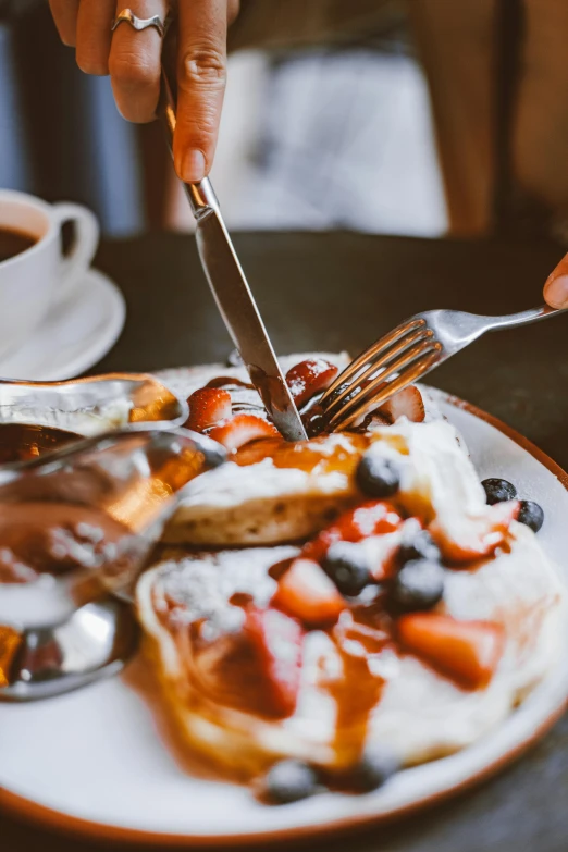 a hand that is  some food with a knife