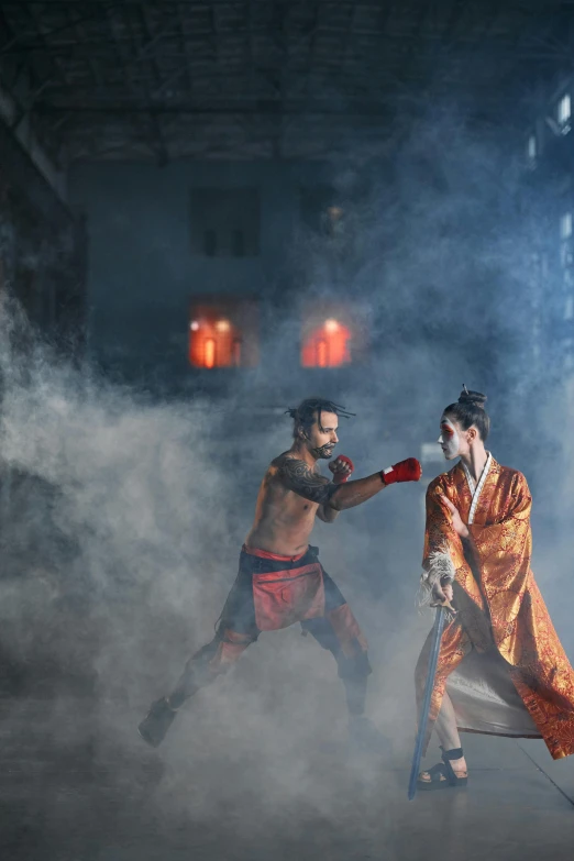 man and woman dressed up in traditional costumes performing martial trick