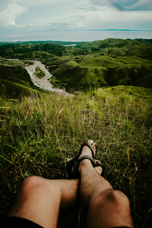 a person laying in the grass and looking over the valley