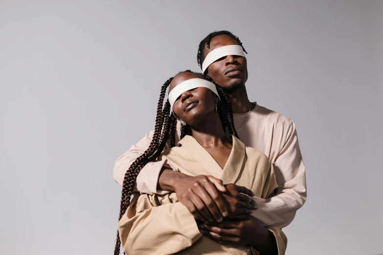 two people standing next to each other wearing blindfolds, trending on pexels, afrofuturism, jesus hugging a woman, siamese twins, servants, [ theatrical ]