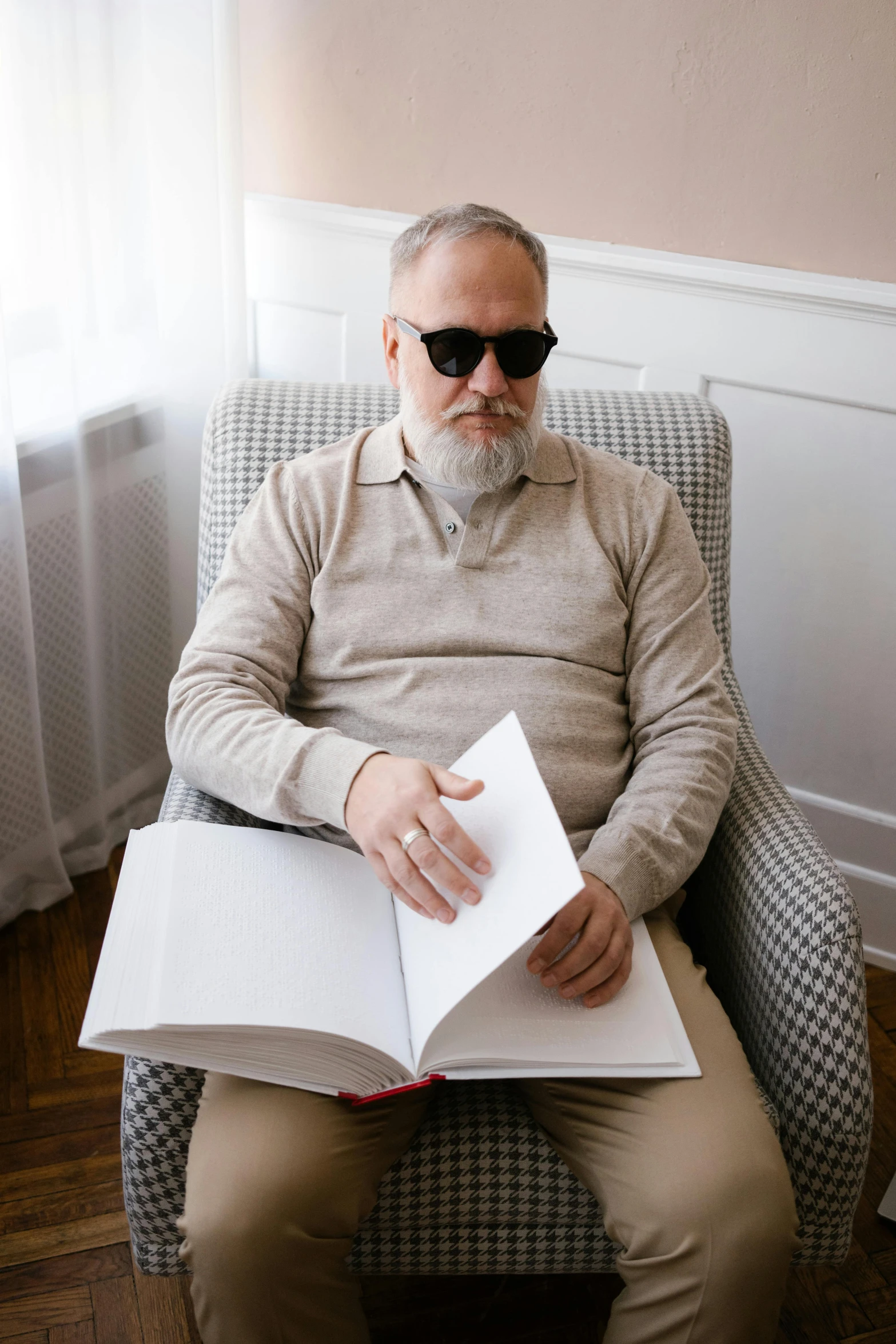 a man sitting in a chair reading a book, an album cover, inspired by Karl Buesgen, unsplash, short white beard, implanted sunglasses, russian academic, gray men
