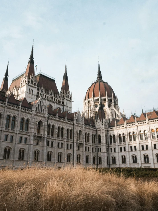 a large building sitting on top of a grass covered field, inspired by Mihály Munkácsy, pexels contest winner, budapest, 🚿🗝📝