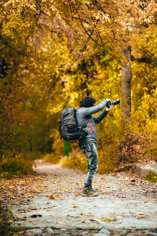 a man taking a picture of himself in the woods, pexels contest winner, rollerblading, during autumn, a backpack, dabbing