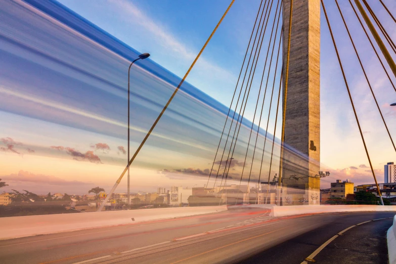 the sun setting on a bridge overpass near a highway