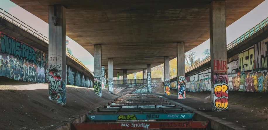 a train track covered in graffiti under a bridge, inspired by Thomas Struth, unsplash contest winner, at a skate park, landscape of flat wastelands, neo brutalism, benches