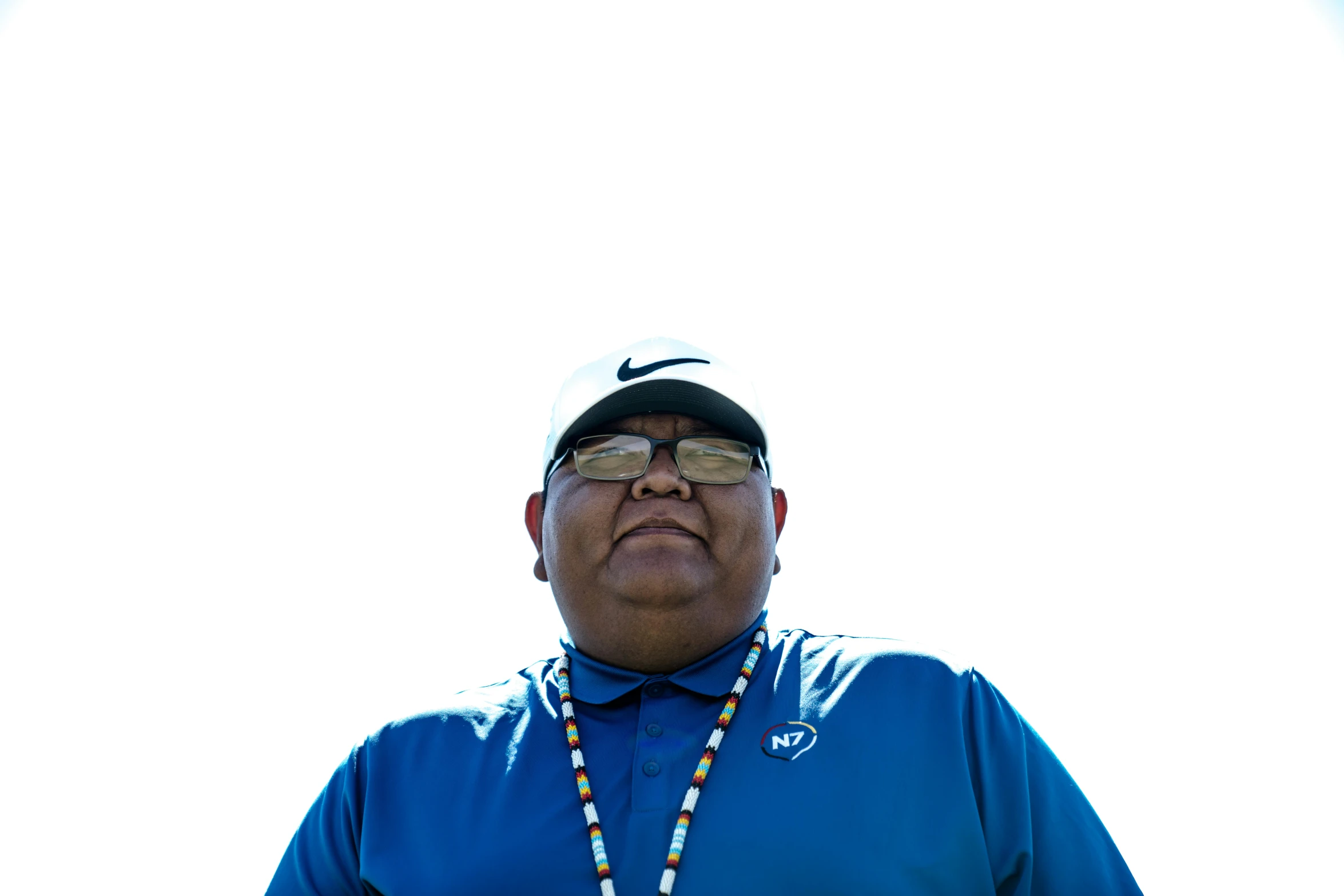 a man with a blue shirt and blue beaded necklace