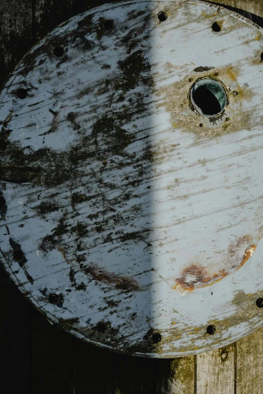 a smiley face painted on the side of a wooden fence, an album cover, inspired by ashley wood, unsplash, water texture, watertank, ((rust)), difraction from back light