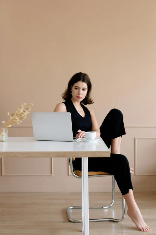 a woman sitting at a table with a laptop, sitting on top a table, wearing black modern clothes, - 9