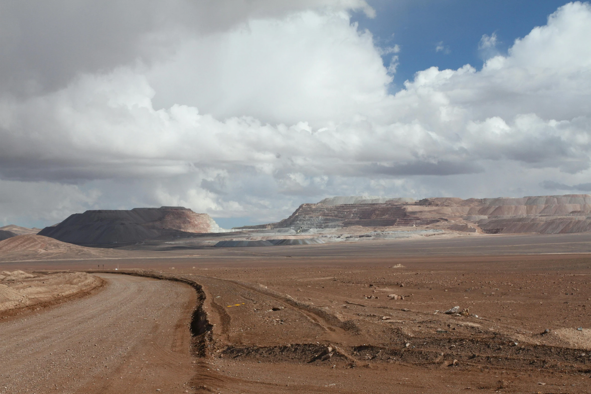 a long dirt road next to a mountainous landscape