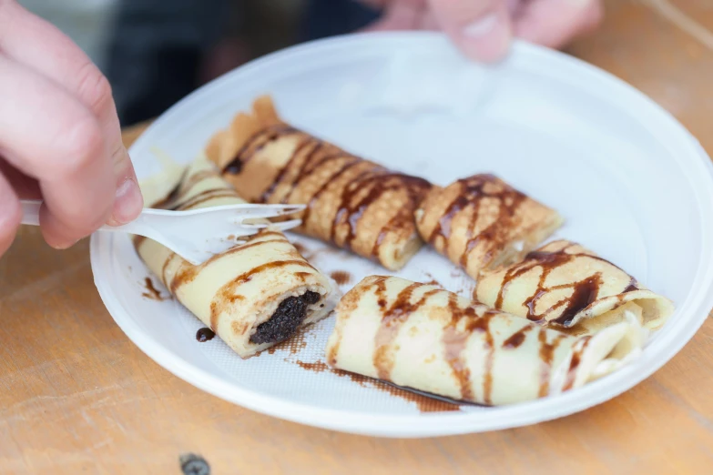 a man  a pastry with tongs on a white plate