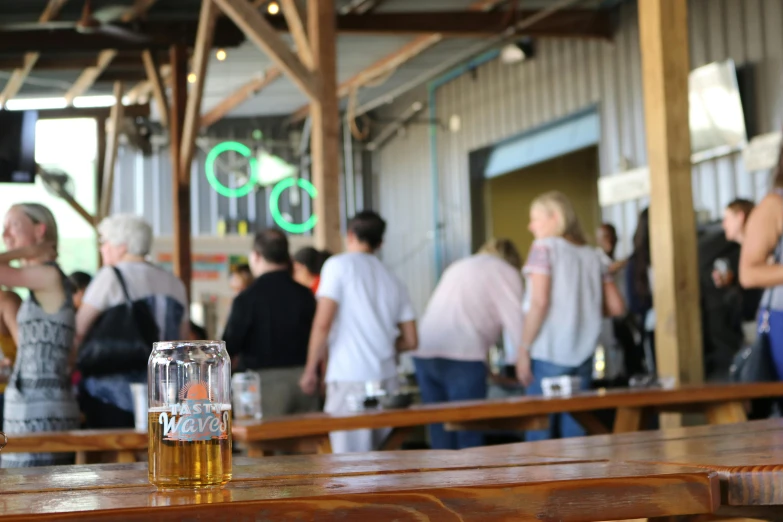 a beer glass sitting on top of a wooden table, lots of people, whealan, market setting, carson ellis