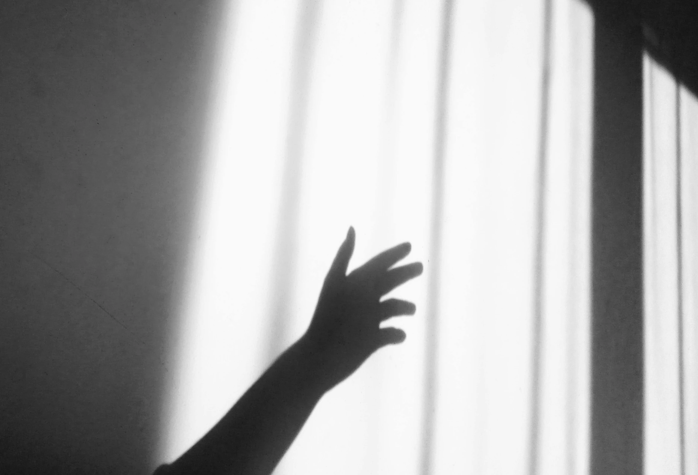 a black and white photo of a person reaching out of a window, light and space, soft shadow, holding hand, claw, uploaded