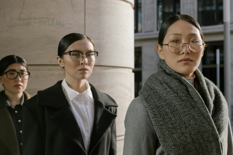 a group of people standing in front of a building, inspired by Wang Duo, serial art, female lawyer, glasses without frames, two models in the frame, looking serious