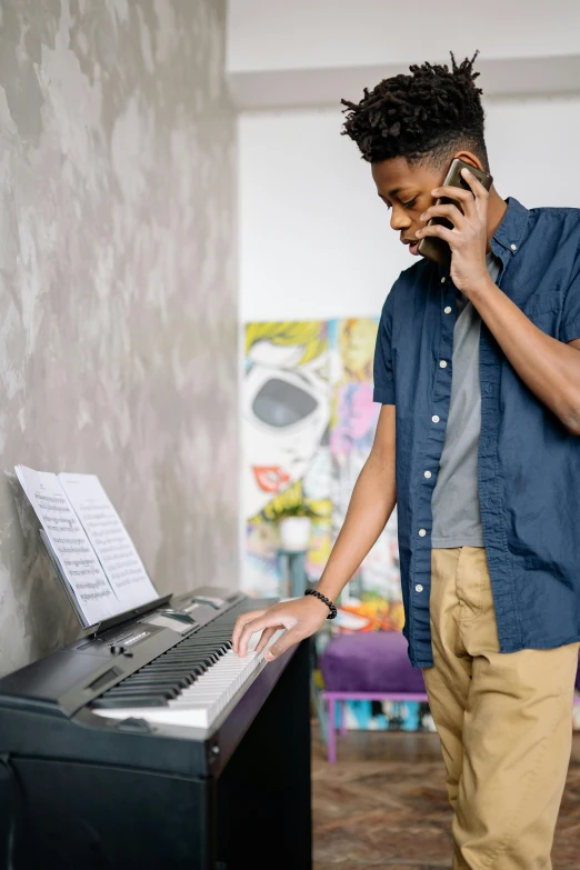 a man standing next to a piano talking on a cell phone