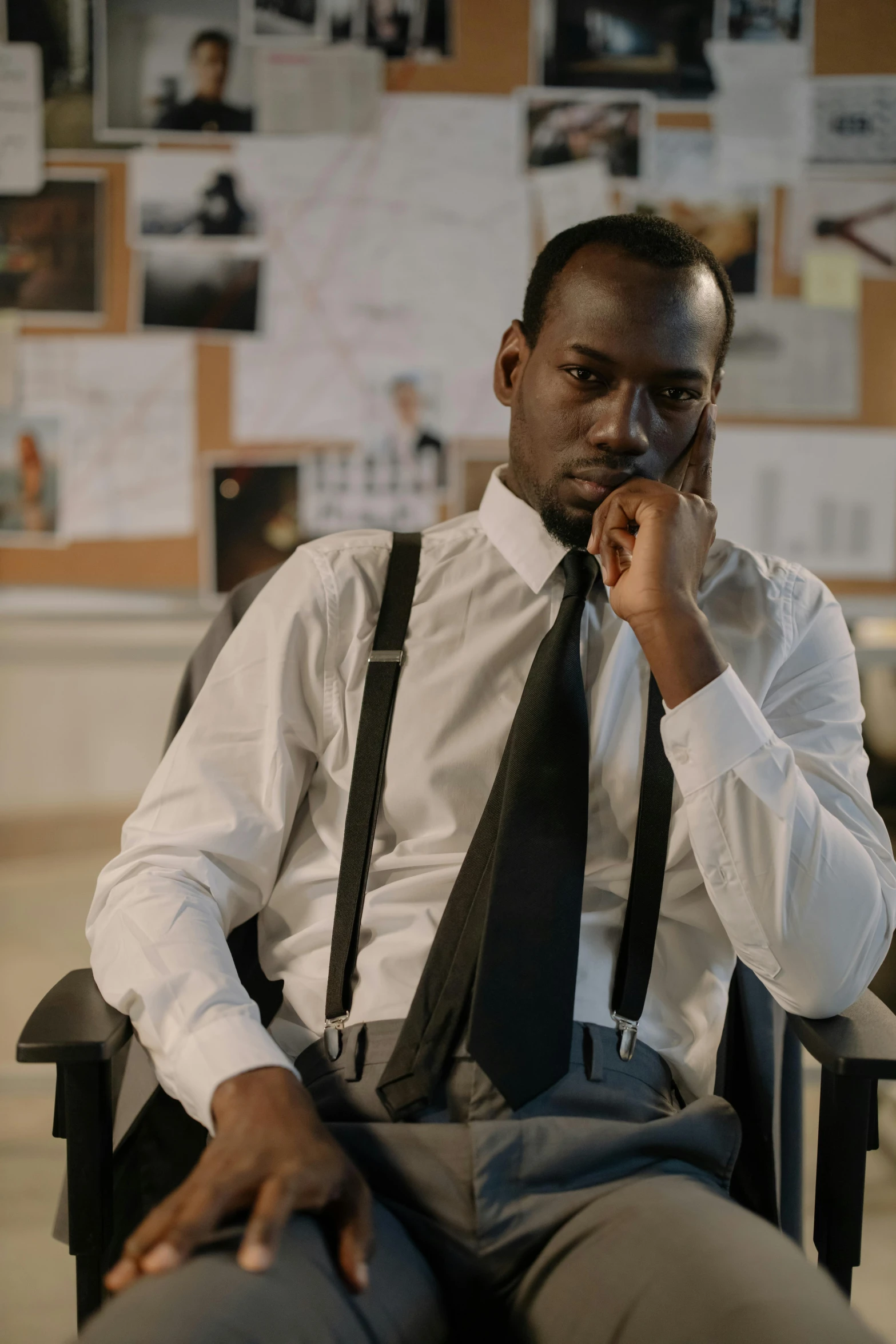 a man sitting in a chair talking on a cell phone, adut akech, dress shirt and tie, looking serious, lgbtq