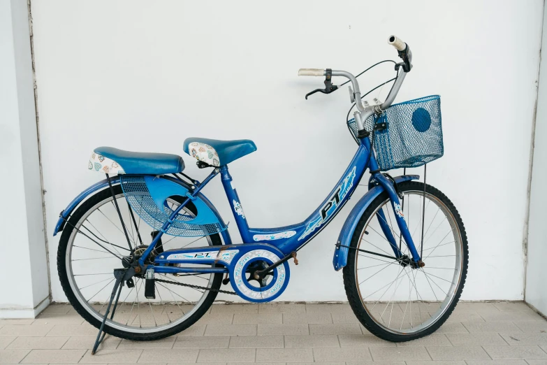 a blue bicycle parked against a white wall, an album cover, by Carey Morris, pexels contest winner, shin hanga, side front view, family friendly, taiwan, shiny crisp finish