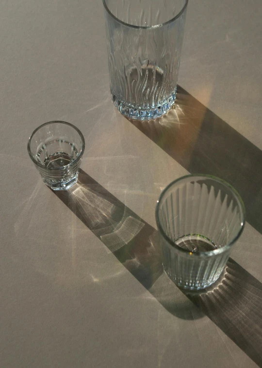 three s glasses are casting a shadow on a table