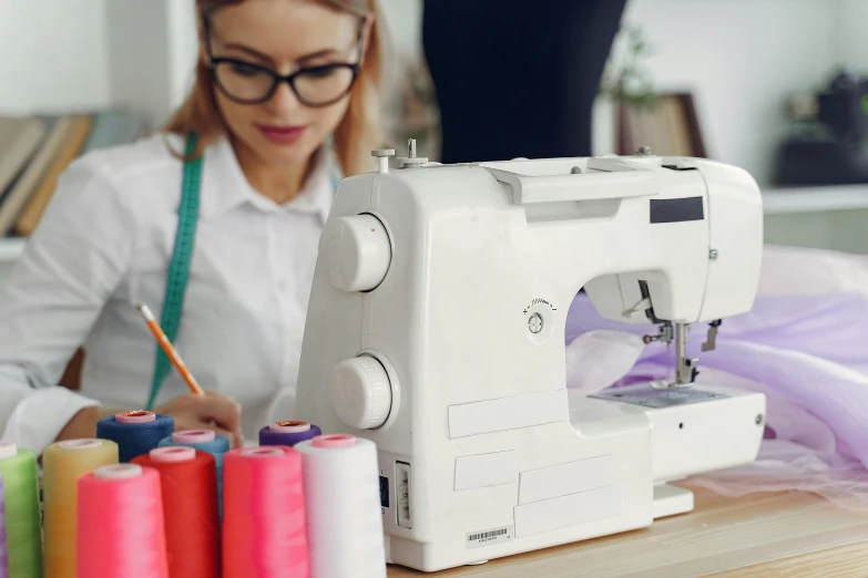 a woman working at a sewing machine with colorful thread spools