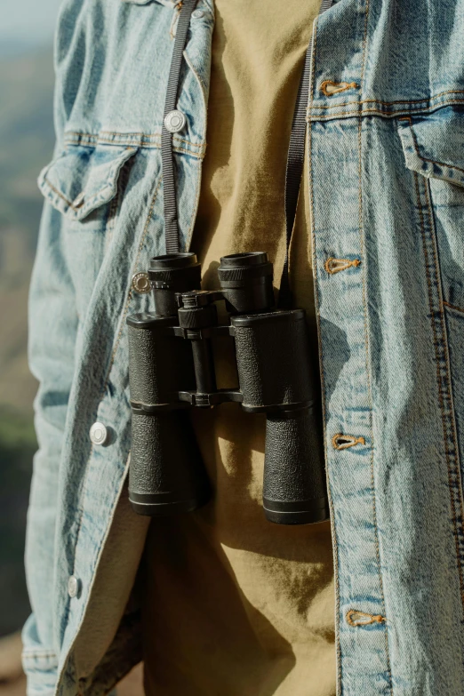 a person in denim jacket holding four binoculars