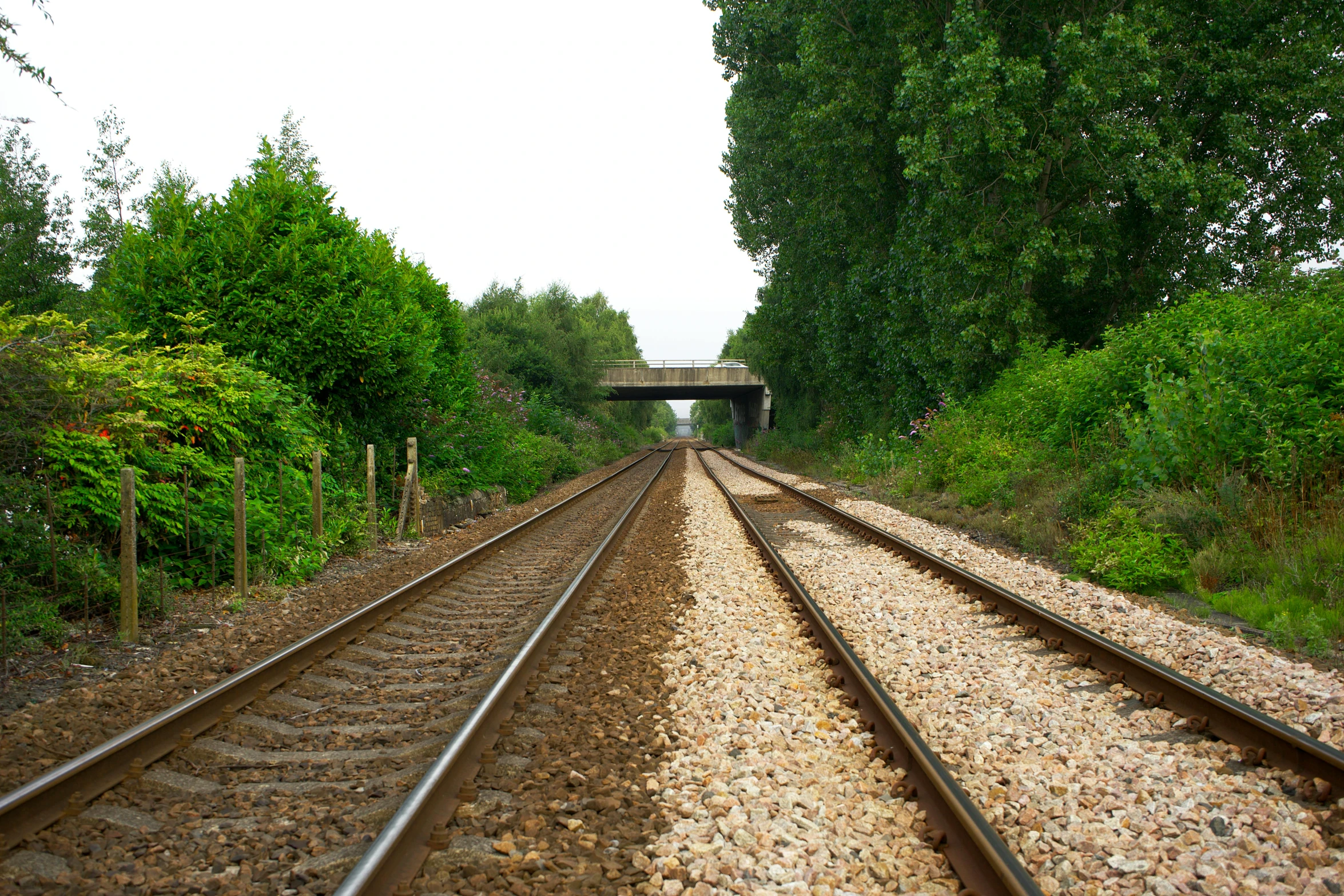 a train track with a bridge in the background, taken on a 2010s camera, northern france, realistic »