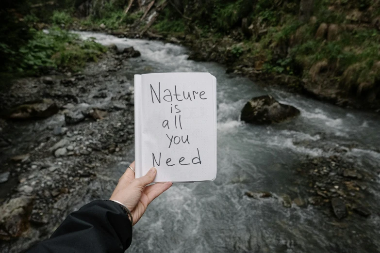 a hand holding a note that says nature is all you need