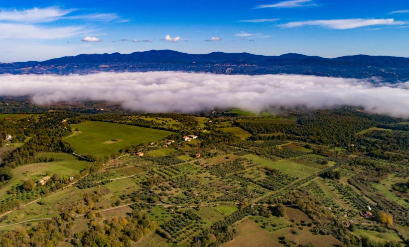 an aerial view of a valley with mountains in the background, by Julian Allen, pexels contest winner, renaissance, cotton clouds, lourmarin, mist low over ground, giorgetto giugiaro