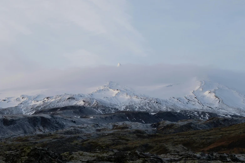 snow covered mountains stand above a grassy area