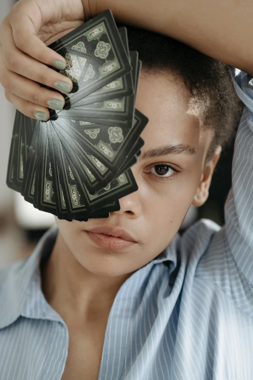 a woman holding a bunch of money in front of her face, an album cover, inspired by Hedi Xandt, pexels contest winner, renaissance, playing cards, black teenage boy, symmetrical tarot card, androgynous person