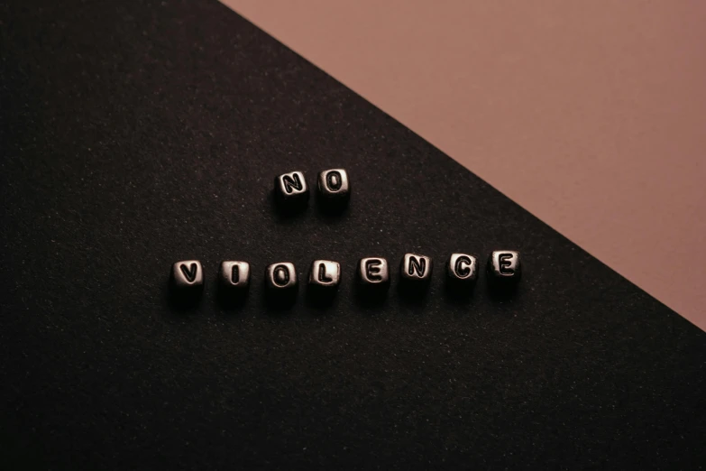 the word violence spelled with cubes on a black surface, an album cover, by Caro Niederer, trending on pexels, beads, background image, white ribbon, teenage no