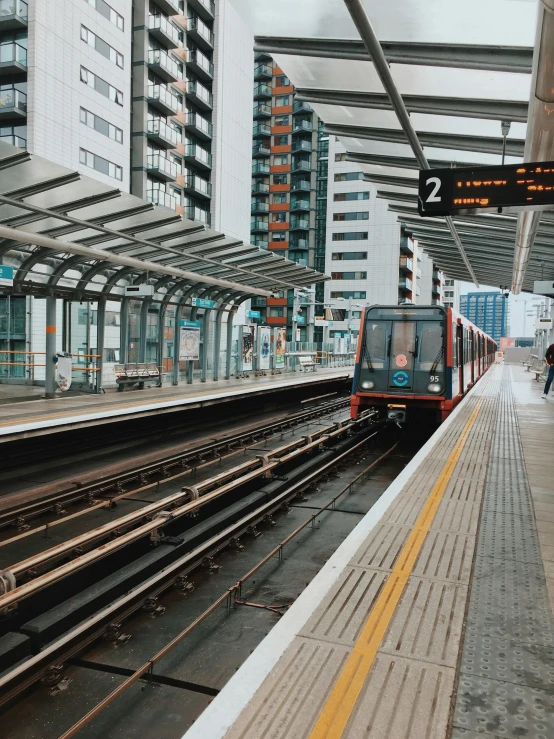 a train pulling into a train station next to tall buildings, unsplash, london south bank, thumbnail, low quality photo, 🚿🗝📝