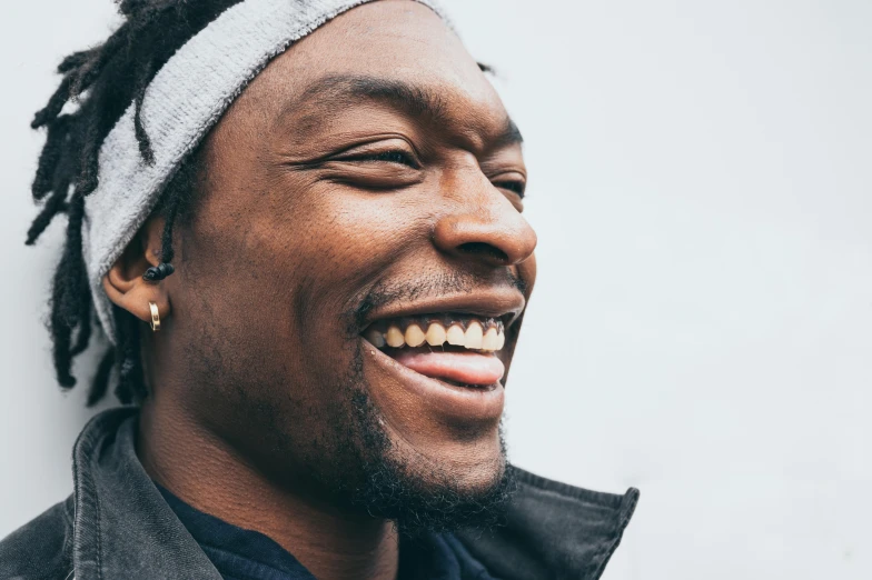 man smiling with dreadlocks and gray jacket on