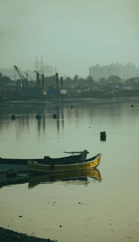 a couple of boats sitting on top of a lake, by Sudip Roy, distant cityscape, reflects, raw file, yellow