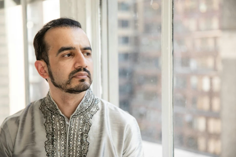 man in indian clothing looking out of window