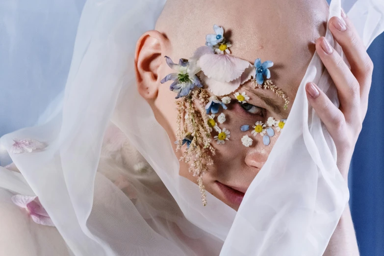 a woman with face makeup and veil with flowers on her face