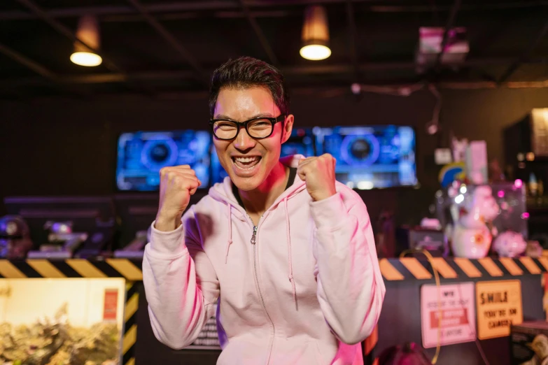 a man in a pink hoodie giving a thumbs up, pexels contest winner, happening, arcade game, like andy lau, avatar image, standing in a starbase bar