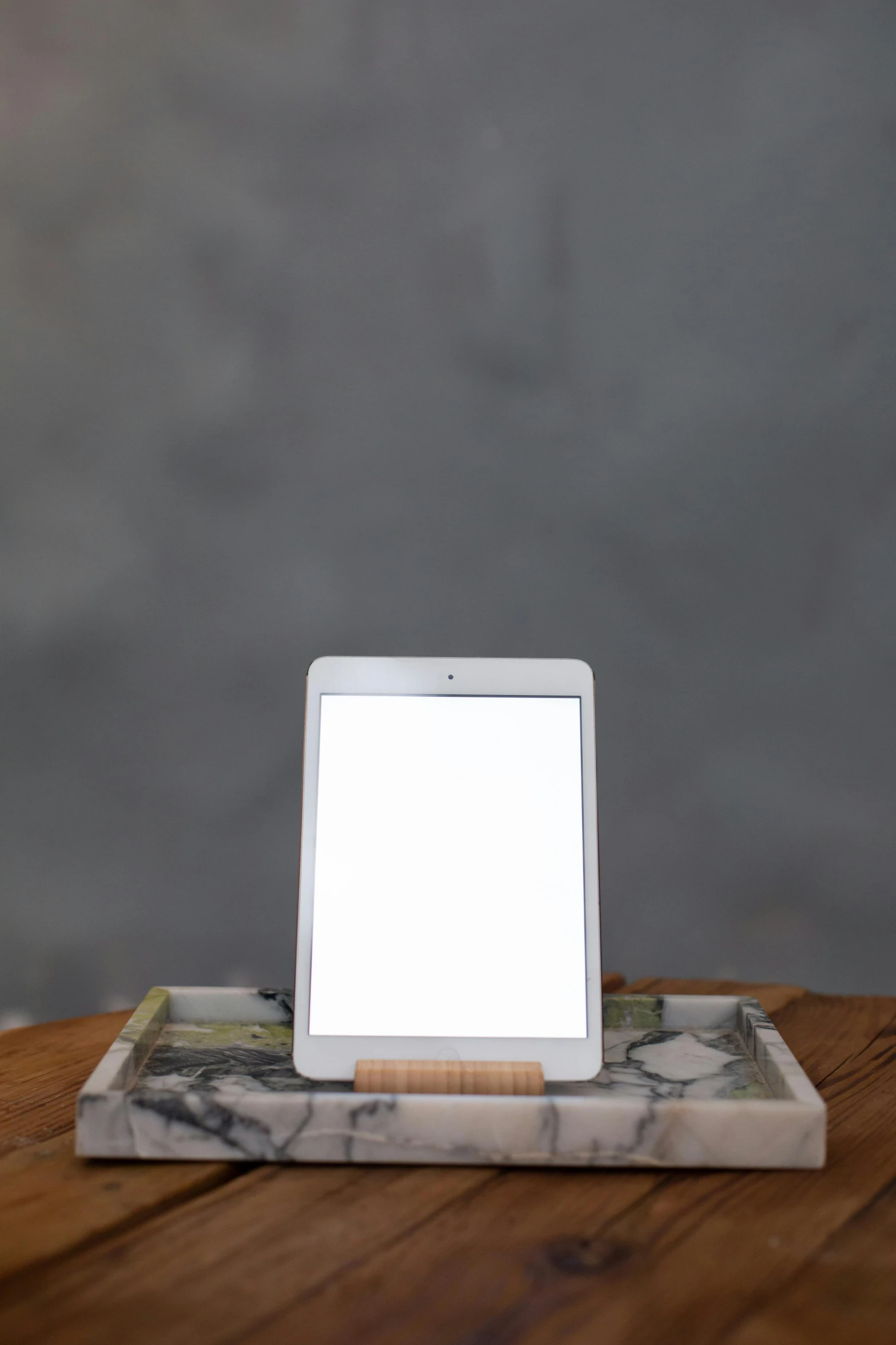 a tablet computer sitting on top of a wooden table, a portrait, by Carey Morris, light and space, white marble, single light, medium-shot, 1 2 9 7