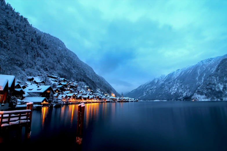 a snow covered lake with lit up buildings near it