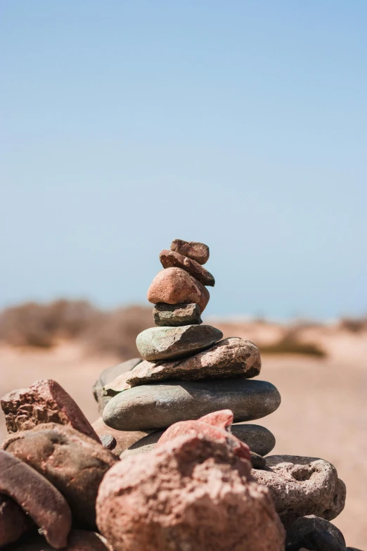 a pile of rocks sitting on top of a sandy beach, at the desert, red sandstone natural sculptures, urban surroundings, afar