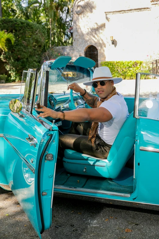 a person wearing white driving a blue car