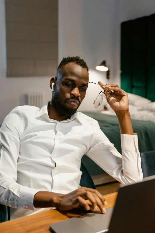 a man sitting in front of a laptop computer, trending on pexels, renaissance, brown skin man egyptian prince, wearing white shirt, lgbtq, big forehead