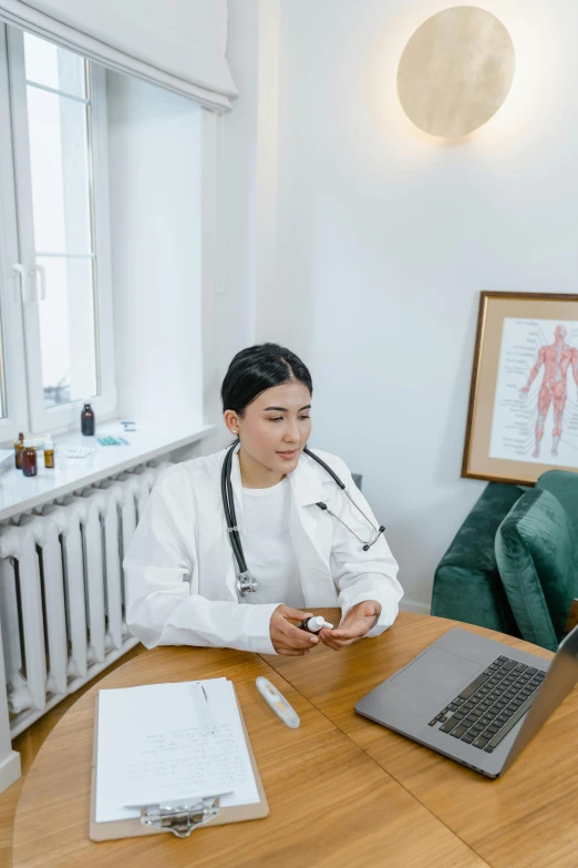 a woman sitting at a table in front of a laptop, white coat, asian male, taken on iphone 1 3 pro, quack medicine