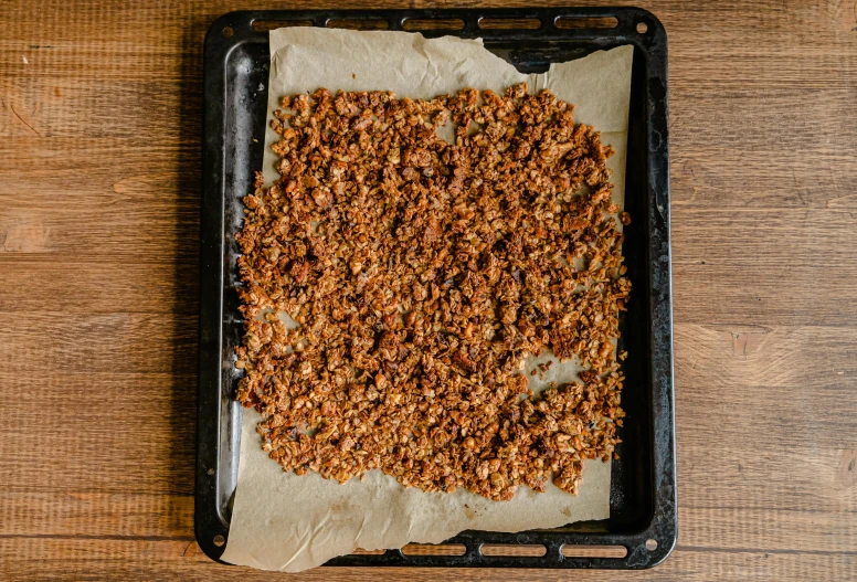 a pan filled with granola sitting on top of a wooden table, a portrait, by Jan Tengnagel, pexels, square, grid, terracotta, very large