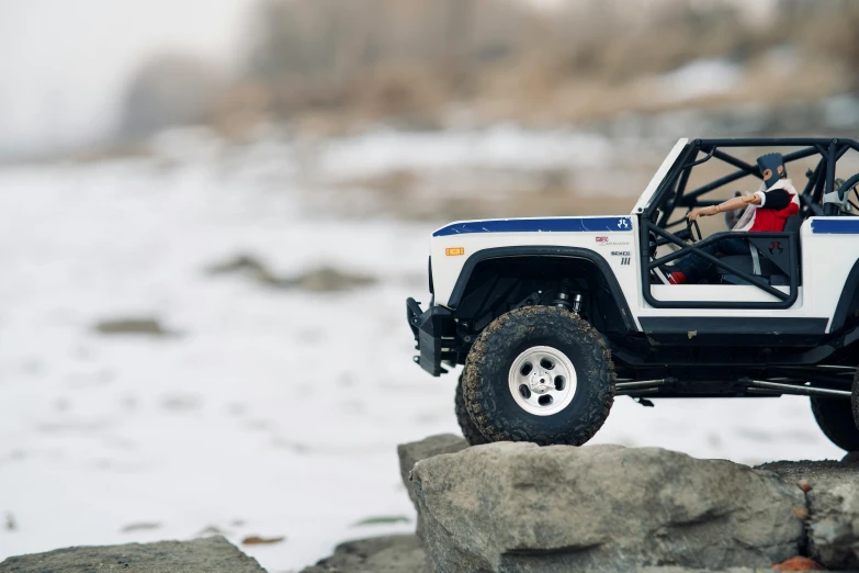 a close up view of a jeep driving on rocks with the door open