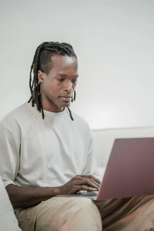 a man sitting on a couch using a laptop, by Cosmo Alexander, trending on unsplash, himba hairstyle, lgbt, on a white table, official screenshot