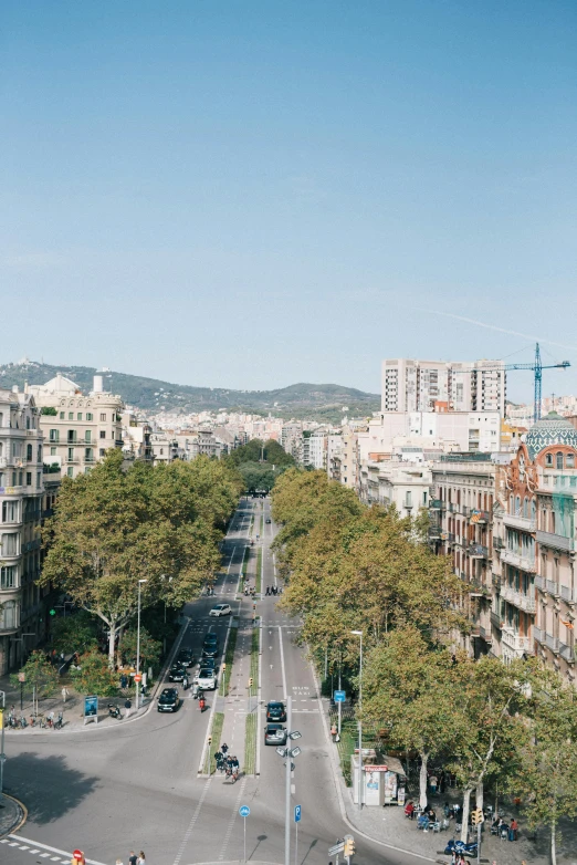 a city street filled with lots of traffic next to tall buildings, inspired by Tomàs Barceló, unsplash contest winner, art nouveau, 4 k cinematic panoramic view, square, southern european scenery, wide high angle view